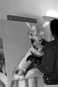 photo noir et blanc de céline leynaud en train de peindre un tableau de corps femme de peinture acrylique au pinceau sur toile de peinture contemporaine